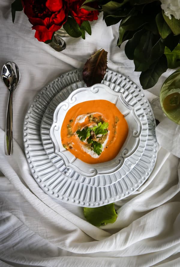 curried cauliflower soup in a white bowl on two plates garnished with cilantro