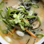 a bowl of miso soup with shiitake mushrooms celery carrots ginger garlic and miso