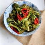 bowl of roasted broccoli with red peppers on a napkin