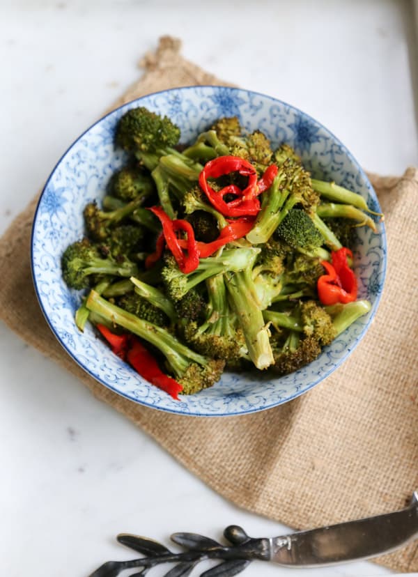 Roasted Broccoli with Lemon and Butter in a blue and white plate with peppers 