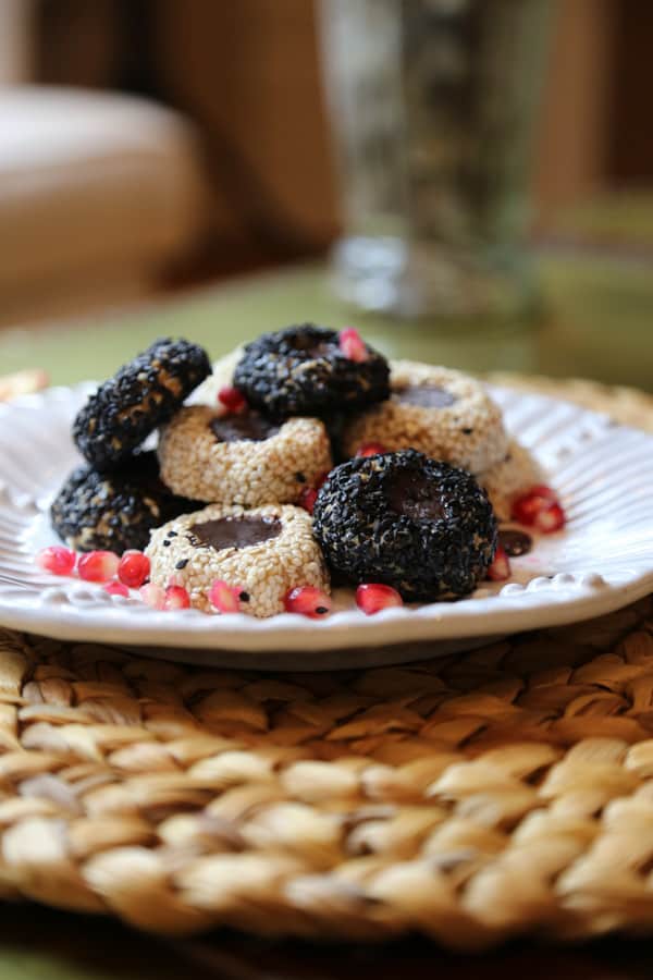 Raw tahini cookies on plate with pomegranate seeds.