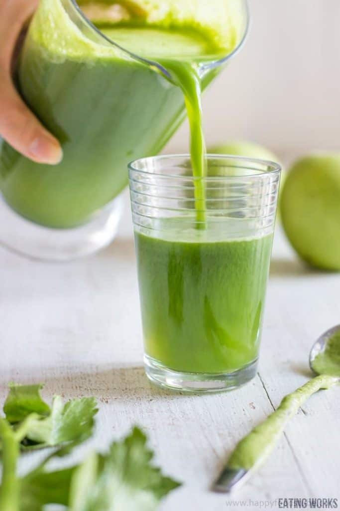 Vegetable juice being poured into a glass from a pitcher