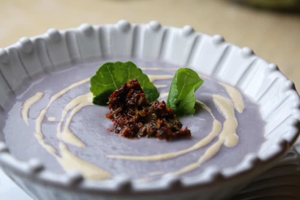 simple cauliflower soup on a plate garnished with mint and tapenade 