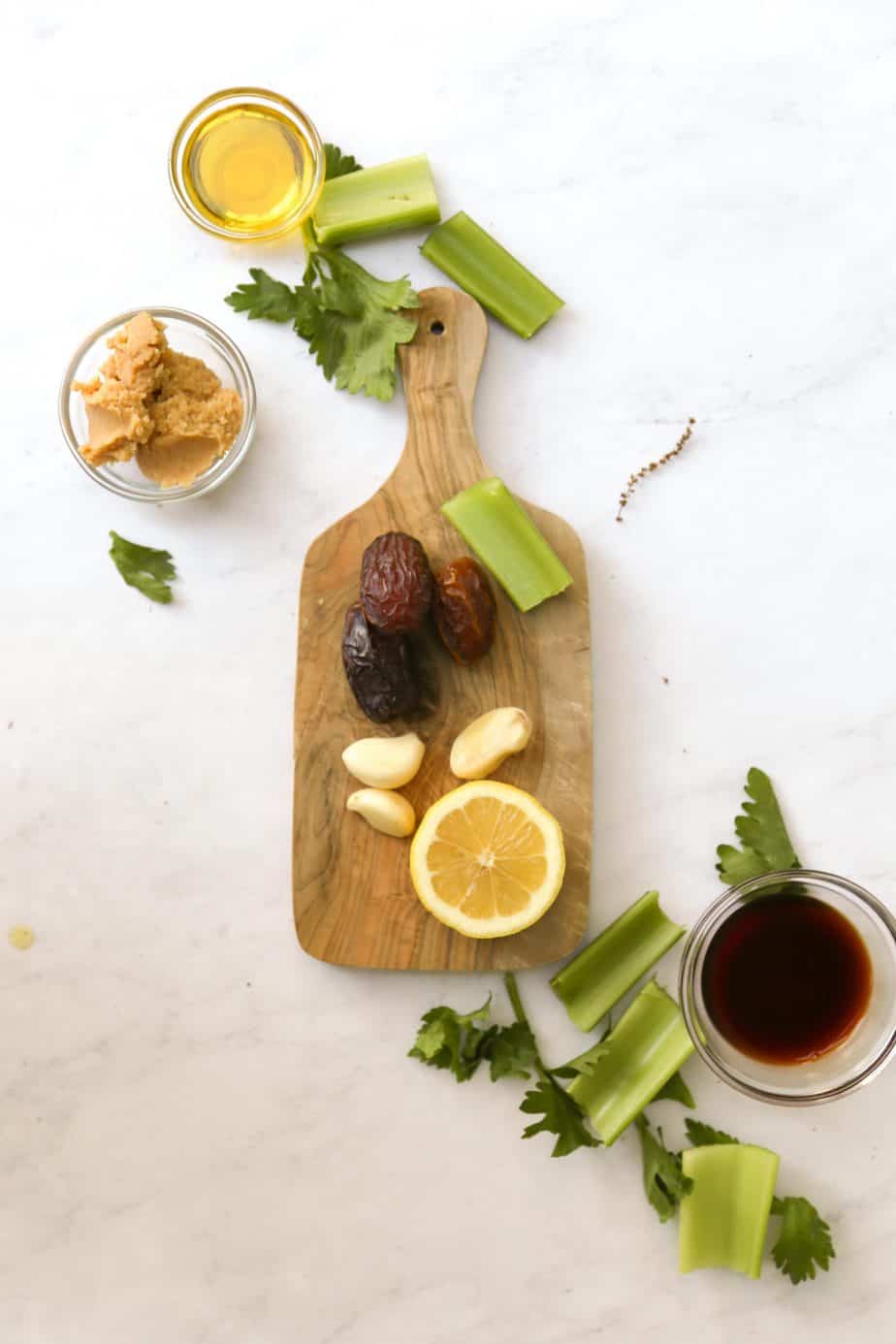 ingredients for dairy free Caesar Dressing on a cutting board lemons celery garlic and dates 