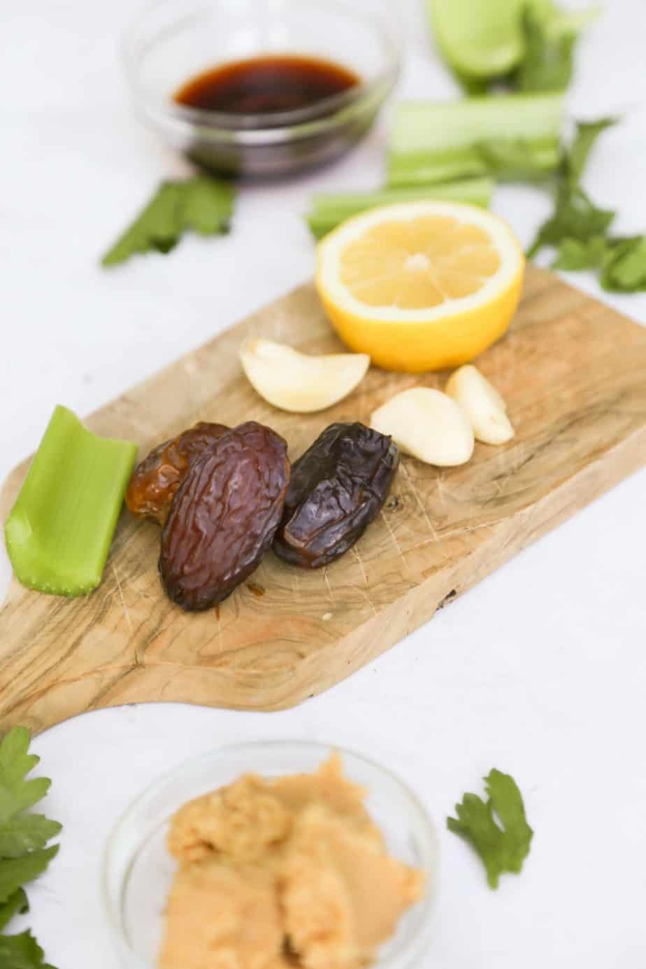 Ingredients for dairy free Ceasar dressing on a cutting board, dates lemon garlic and celery