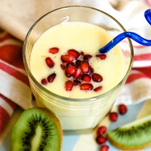 mango and banana smoothie in a glass with kiwi and blue straw