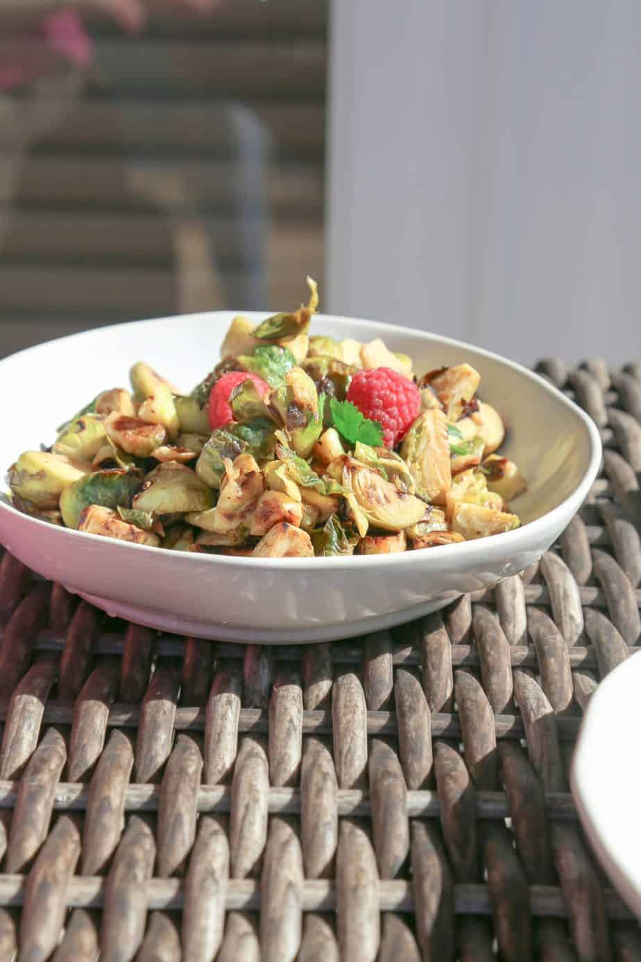 white bowl of Brussels sprouts with raspberries
