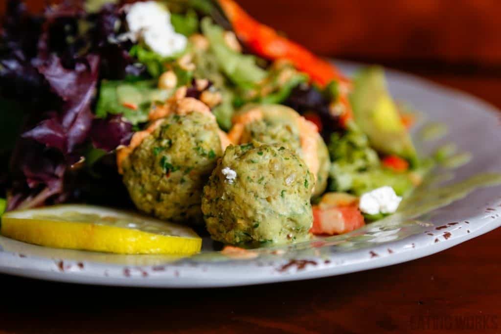 raw vegan falafel recipe. falafel balls on a plate with lemon and a salad