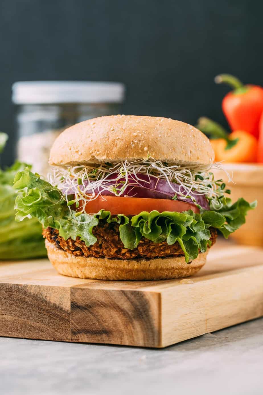 photo of a vegan veggie burger in a bun with lettuce onion and sprouts