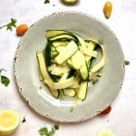 Zucchini Carpaccio with Manchengo Cheese Lemon and Olive Oil on a gray plate