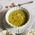 vegan cucumber soup in a white bowl with lemons