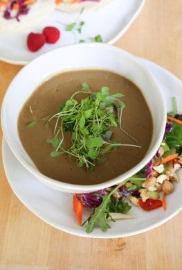 vertical vegan mushroom soup in a white bowl with micro greens