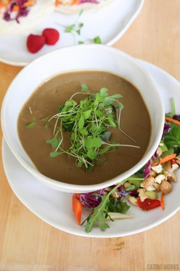 vertical vegan mushroom soup in a white bowl with micro greens.