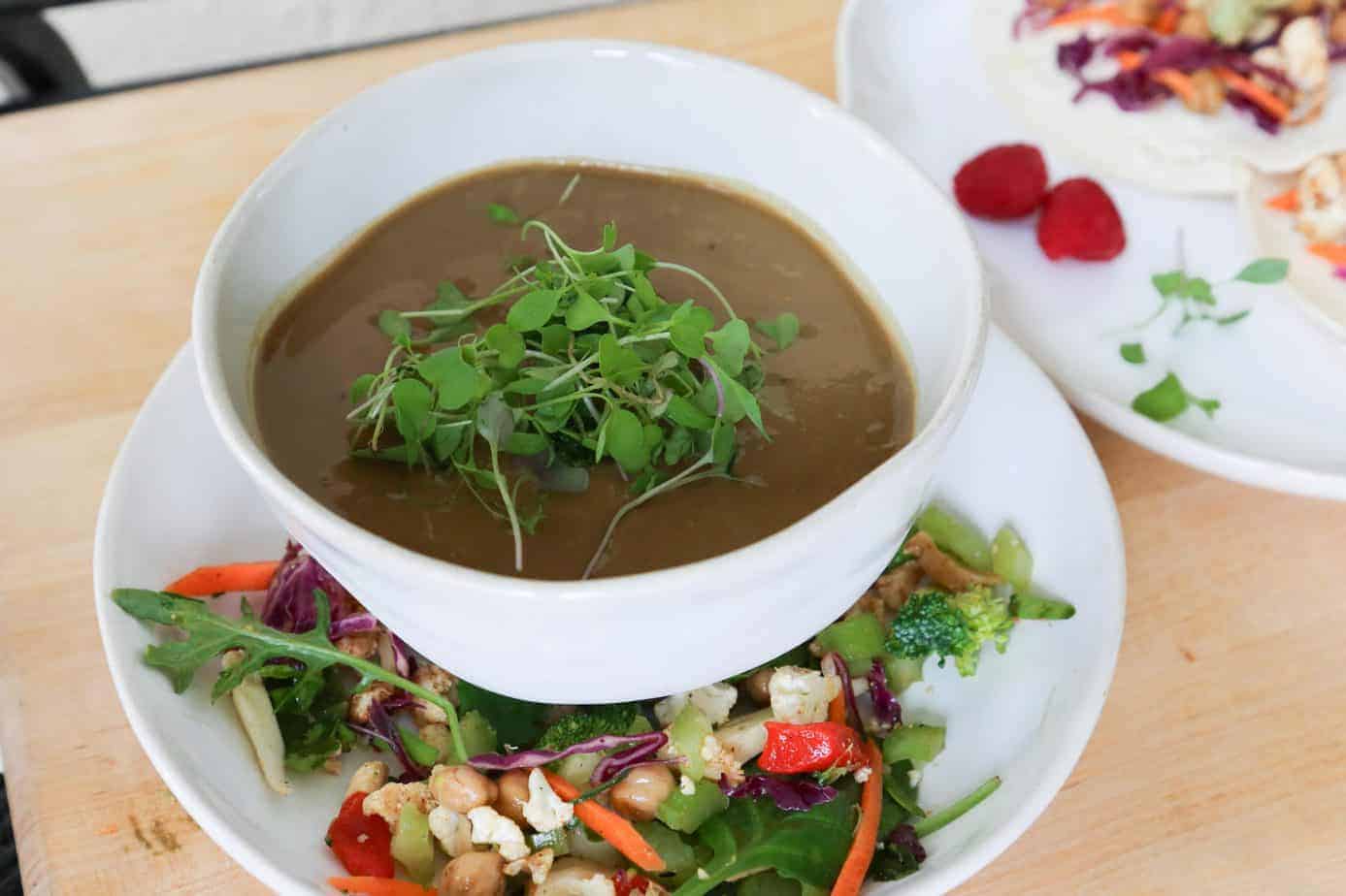 vegan mushroom soup horizontal in a white bowl with Sala with carrots and chickpeas 