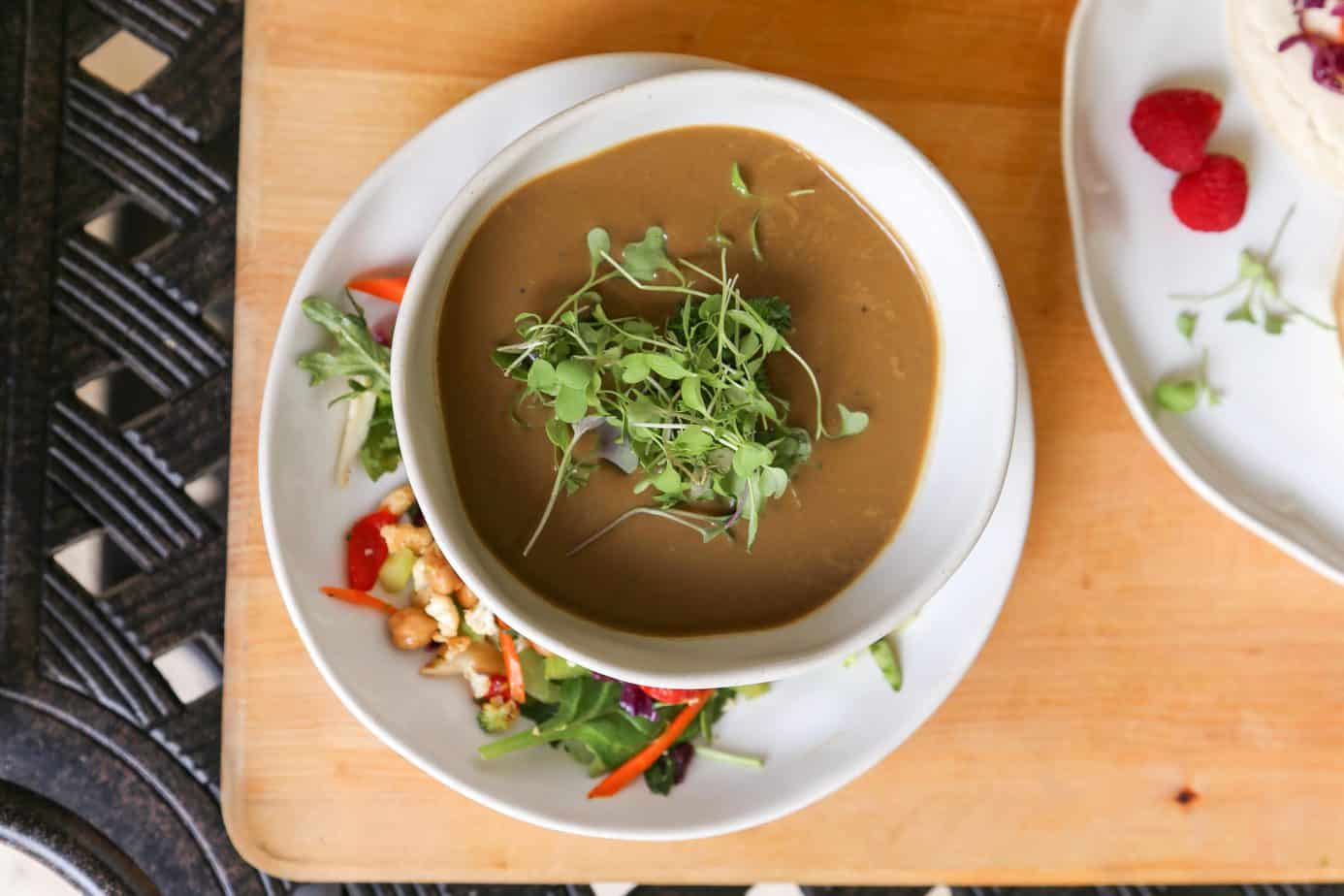vegan mushroom soup in a bowl with micro greens and salad from above 