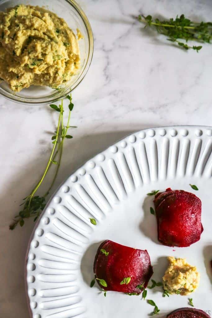 plate of beet ravioli with vegan ricotta on a white plate with thyme garnish from above