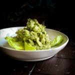 bowl of healthy guacamole with lemon and cilantro with lettuce leaves