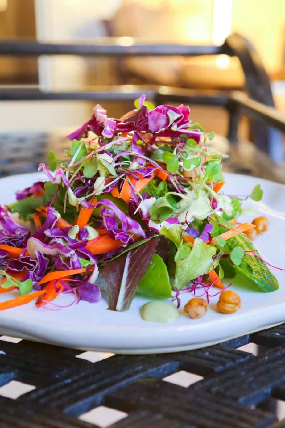 Mixed microgreen salad with roasted chickpeas and green goddess dressing on a white plate 