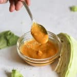 Carrot ginger miso dressing in a clear bowl and on a spoon