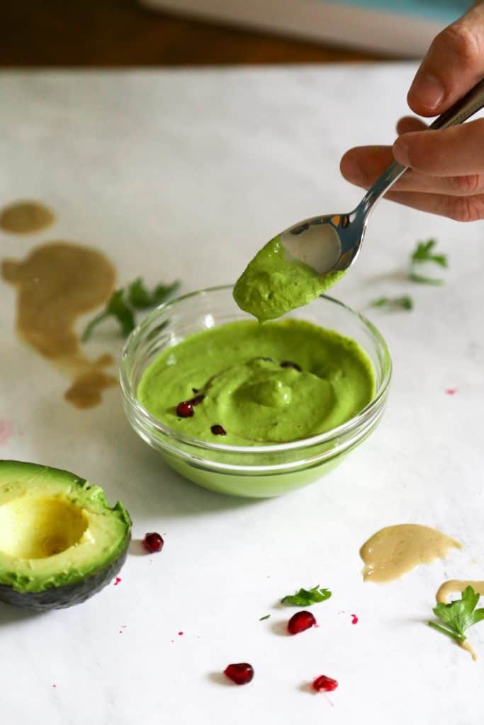 Green tahini sauce on a spoon 