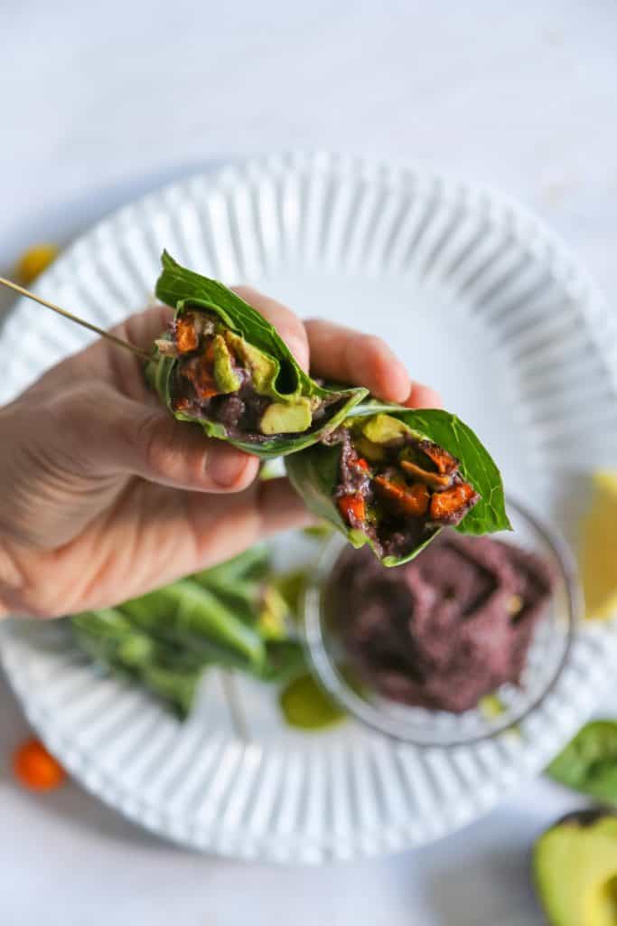 collard green wrap with vegan refried black beans spicy green tahini sauce and cartelized onions and roasted sweet potatoes