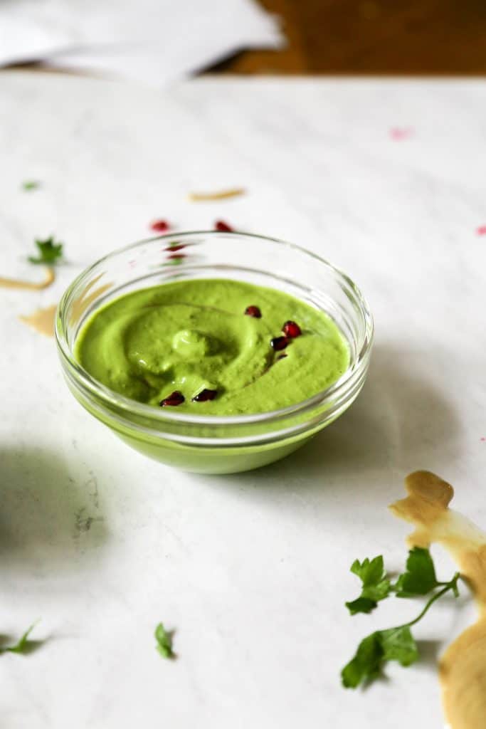 green tahini sauce in a bowl with seeds swirled in