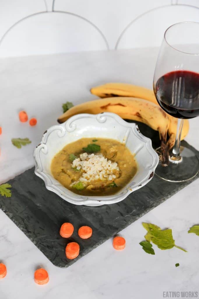 vegan split pea soup recipe from the side in a bowl with wine, bananas, carrots and celery