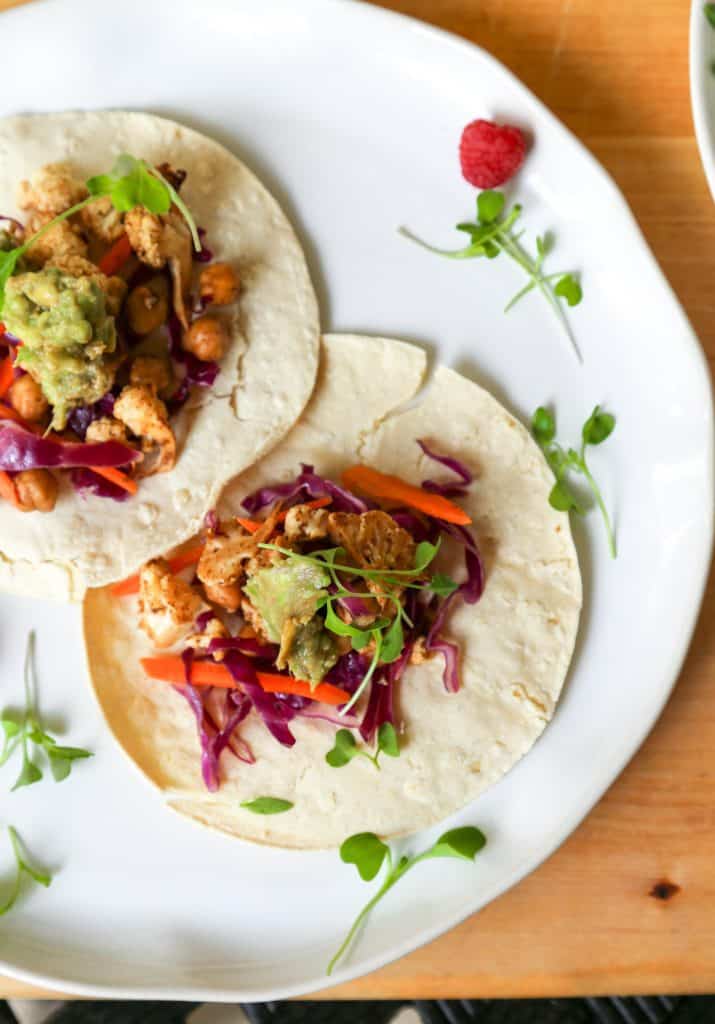 Chickpea Taco with cauliflower Avocado Crema and a cabbage and carrot slaw on a white plate