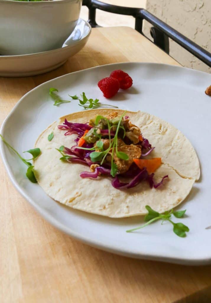 Chickpea Taco with cauliflower Avocado Crema and a cabbage and carrot slaw on a white plate