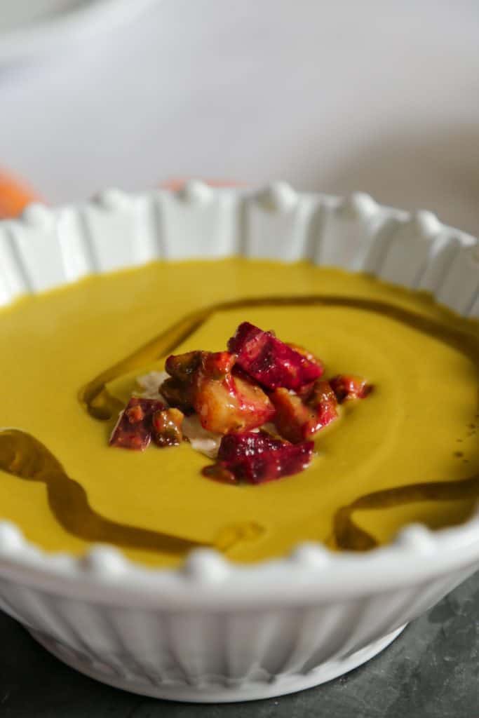 Keto Broccoli and Cheddar Soup in a bowl from the side with broccoli carrots beets onion cabot cheese and water.