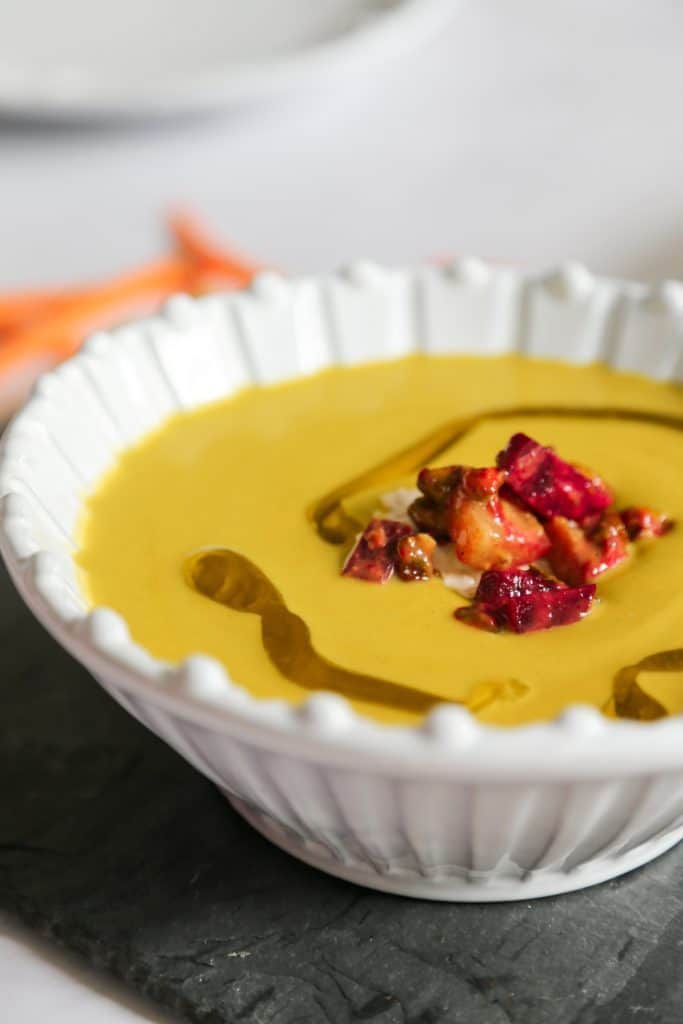 Keto Broccoli and Cheddar Soup in a bowl from the side with broccoli carrots beets onion cabot cheese and water.