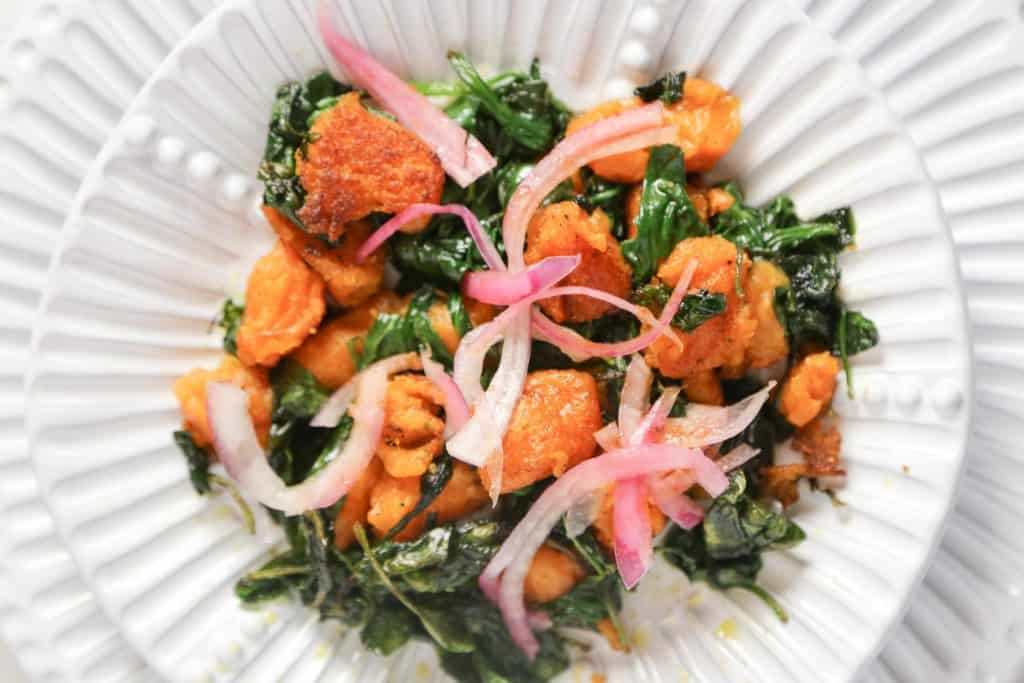 vegan sweet potato gnocchi with sautéed spinach on a white plate made with sweet potatoes and cassava flour