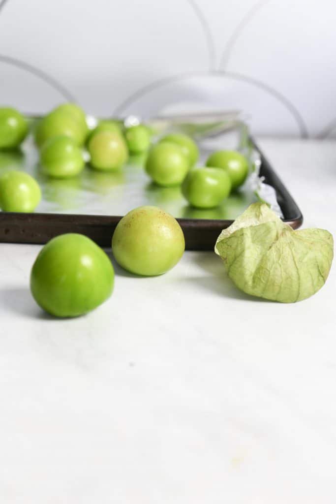 ingredients raw tomatillos on a white counter for spicy tomatillo salsa