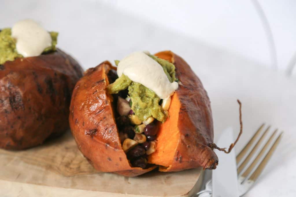 Vegan Stuffed Sweet Potatoes on a plate with a knife and fork. #sweetpotato #vegan #vegansweetpotatorecipe #veganrecipe