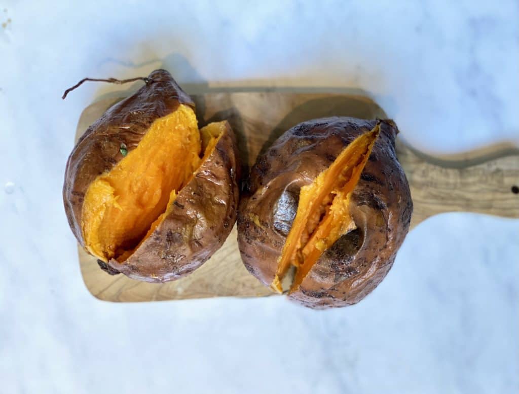 cooked sweet potatoes cut open on a cutting board. 