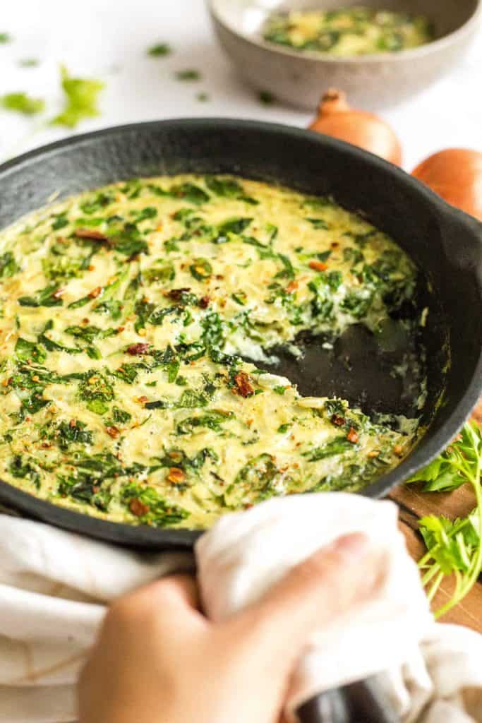 vegan eggless and crustless quiche in a nonstick skillet with greens 