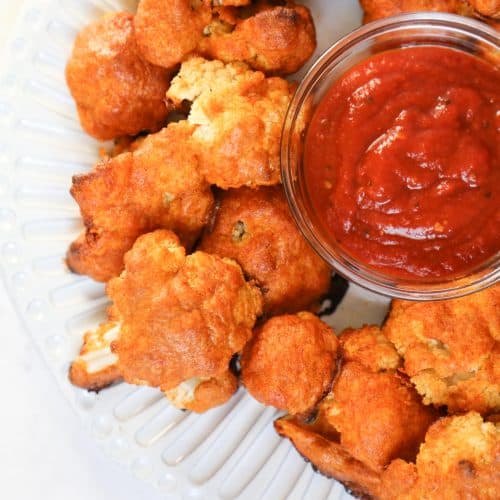 keto cauliflower wings on a white plate with bbq dipping sauce in a bowl