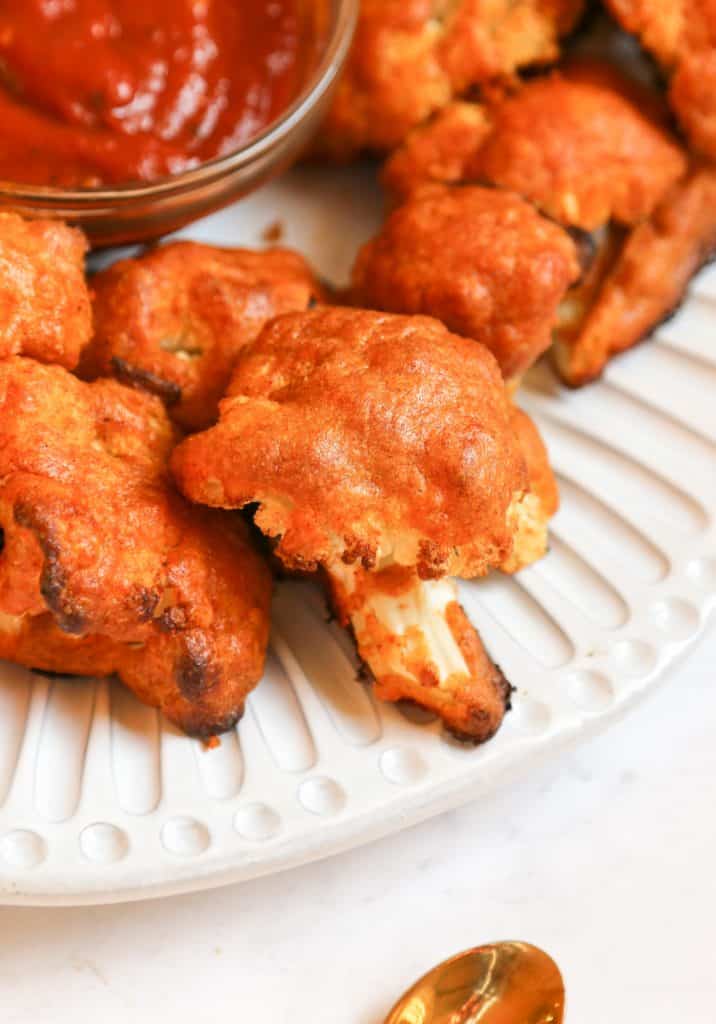 close up shot of keto cauliflower wings on a white plate with bbq dipping sauce