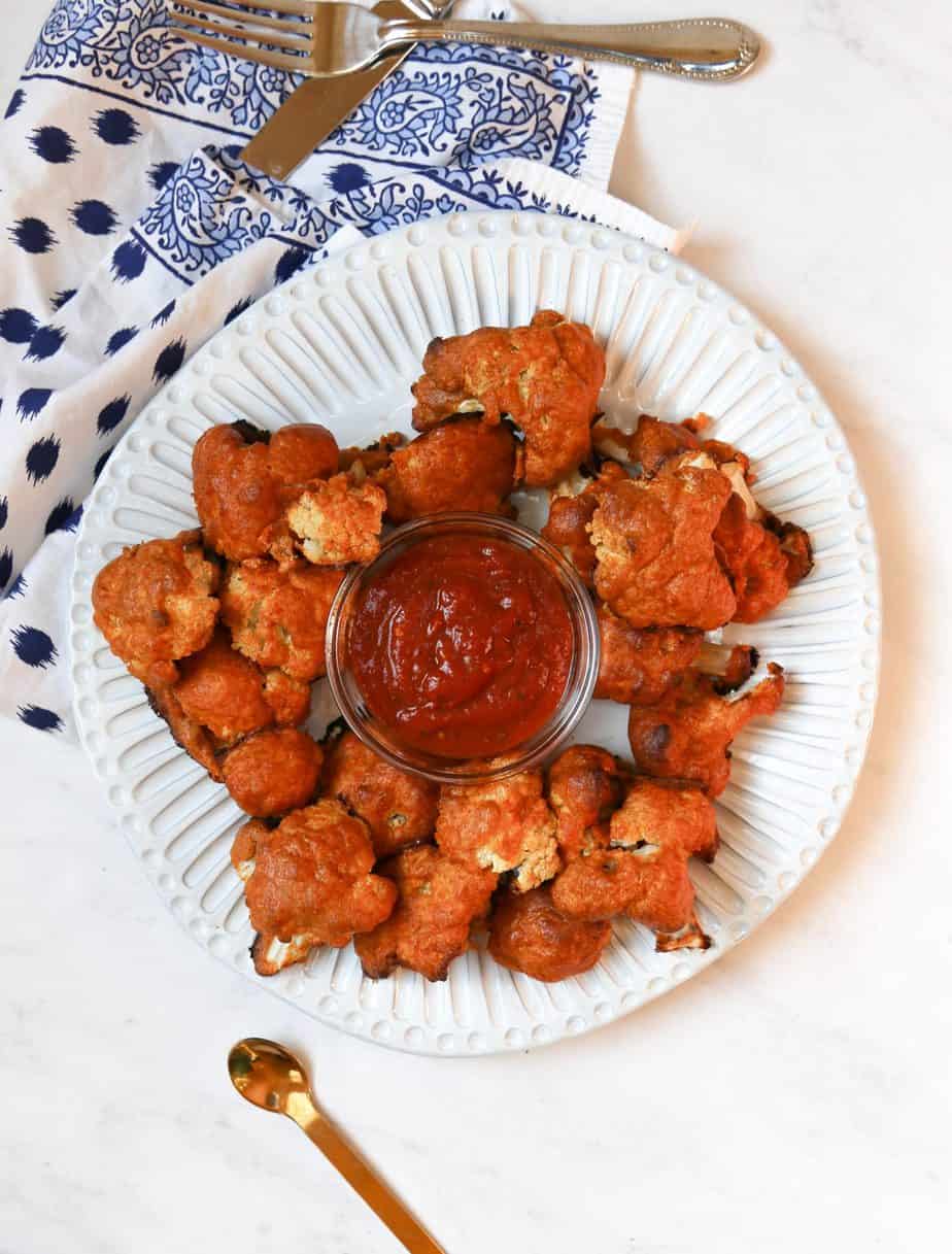 keto cauliflower wings on a white plate with bbq dipping sauce. lazy keto meals.