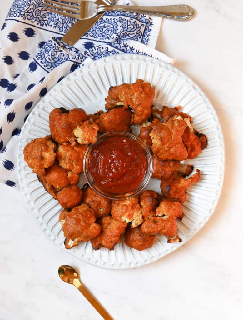 keto cauliflower wings on a white plate with bbq dipping sauce