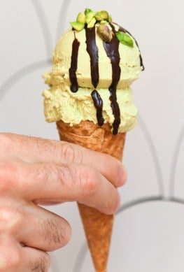 vegan pistachio ice cream on a sugar cone with chocolate syrup