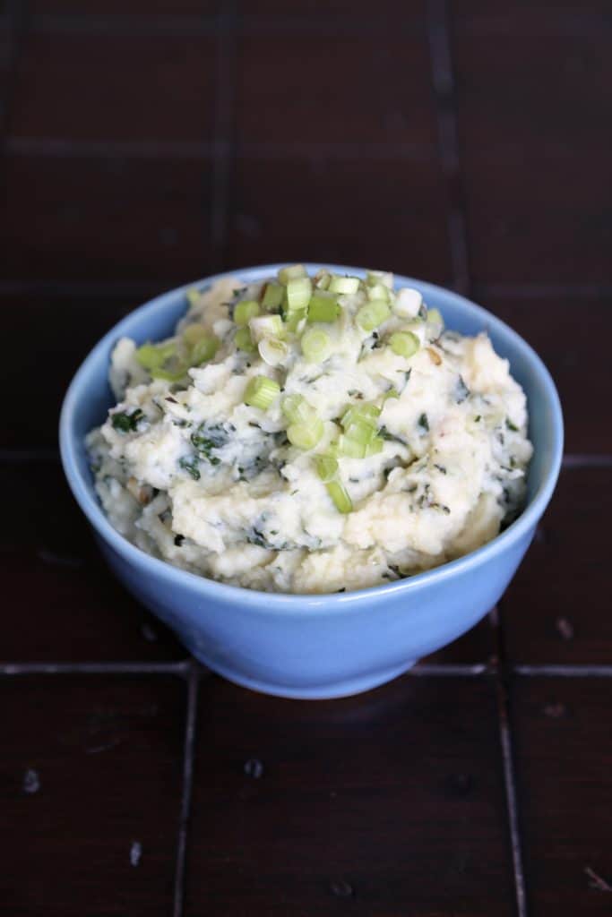 a bowl of parsnip mash with scallions on top.