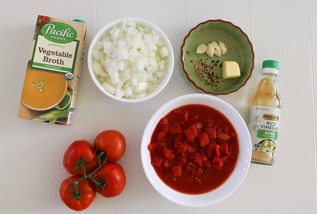 ingredients for gluten free tomato soup, vegetable broth, fresh tomatoes, canned tomatoes, onions, butter, rice vinegar, spices and garlic