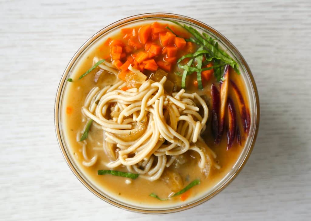 gluten free ramen noodle soup in a bowl with gluten free ramen noodles, carrots, lettuce and onions