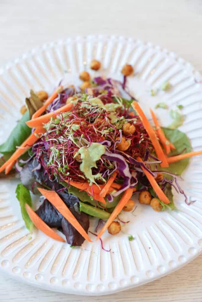 Microgreen Salad with green goddess dressing on a white plate with chickpea croutons