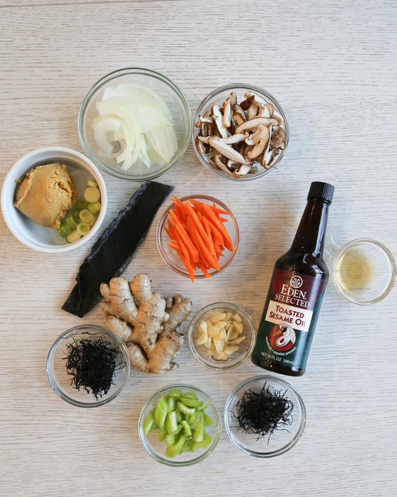 Ingredients for macrobiotic keto and gluten free miso soup, toasted sesame oil, celery, ginger, vinegar, garlic, carrots, wakame, arame, kombu, rice vinegar, mushrooms and miso paste