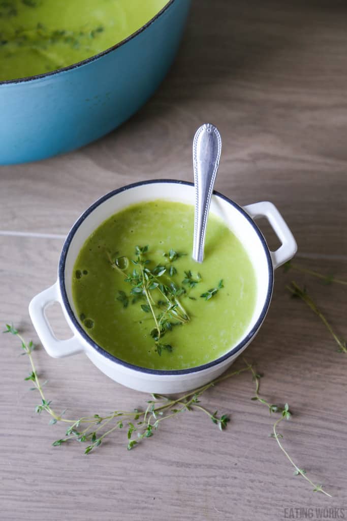 vegan pea soup in a white bowl garnished with thyme