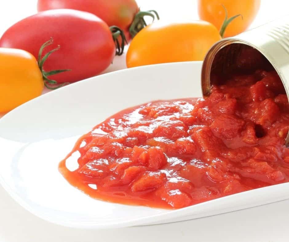 a jar of canned tomatoes spilled onto a white plate 