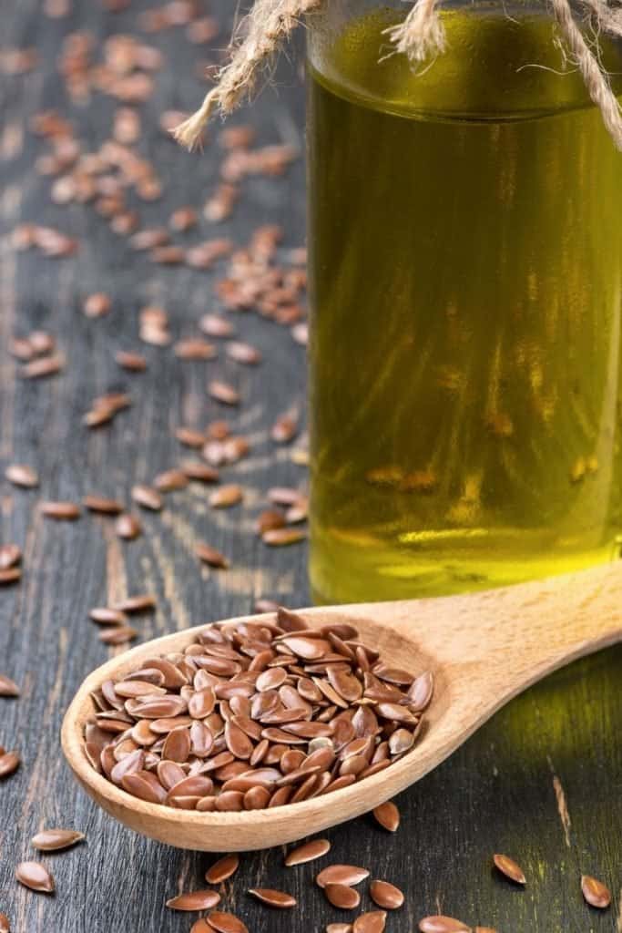 image of flax seeds in a spoon with flax oil in a glass container