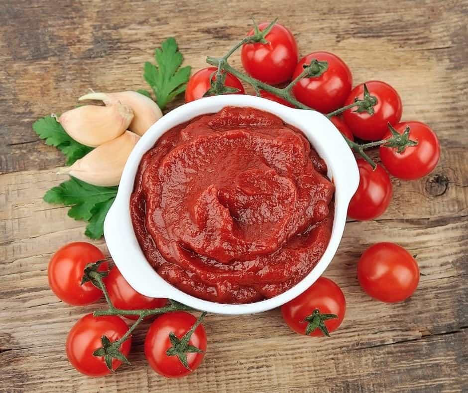 a bowl of tomato paste surrounded by tomatoes 